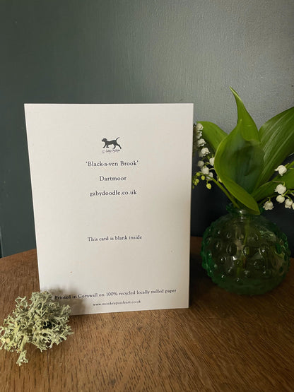 Showing the reverse of a Dartmoor themed greeting card showing the Black a ven brook tumbling through moorland under a sunset sky