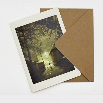 Sticklepath Snow Christmas card showing snow falling at night under a street lamp, a figure and two dogs in the lane